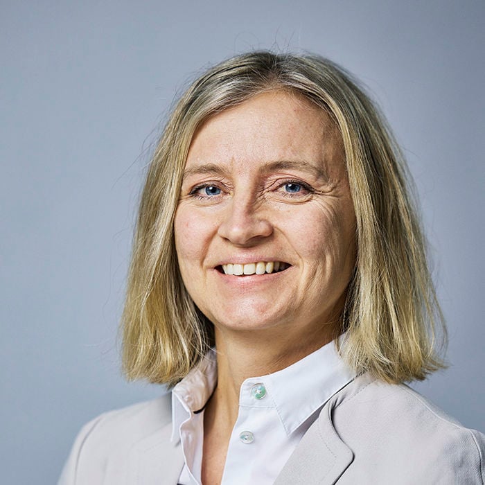 Blid dame med hvit bluse og grå dressjakke